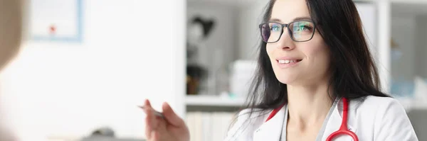 Doctora con estetoscopio en el cuello comunicándose con la paciente en el consultorio — Foto de Stock