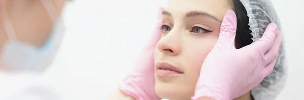 Kosmetikerin blickt auf schwarze Pfeile auf Augen ihrer Kundin — Stockfoto
