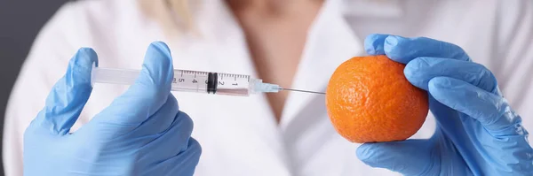 Lekarz kosmetyczka w rękawiczkach wykonujących wstrzyknięcie do pomarańczowego zbliżenia — Zdjęcie stockowe