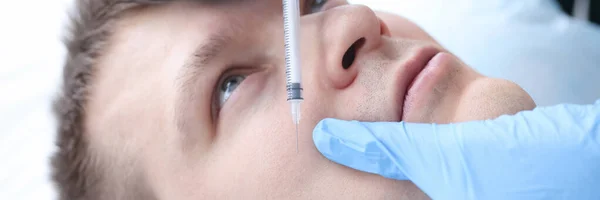 Schoonheidsspecialiste die een injectie geeft in het gezicht van een mannelijke patiënt — Stockfoto