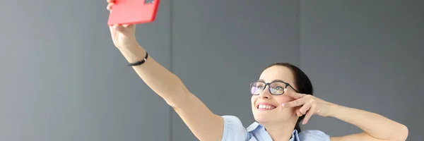 Kobieta w okularach uśmiecha się i robi selfie — Zdjęcie stockowe