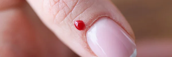 Detailní záběr kapky krve v blízkosti ženských nehtů — Stock fotografie