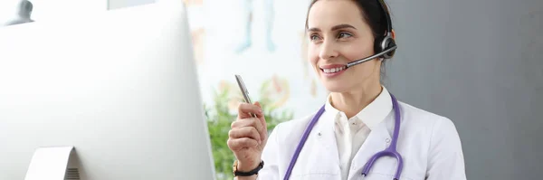 Doktor ve sluchátkách komunikuje s pacientem přes video linku — Stock fotografie