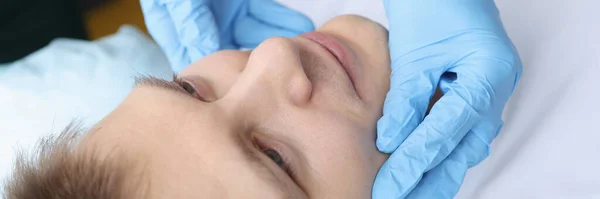 Gloved doctor examines the face of young man — Stock Photo, Image