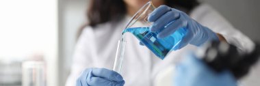 Eldivenli laboratuar teknisyeni test tüpüne kimyasal döküyor.