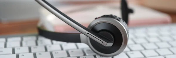 Auriculares negros acostados en el primer plano del teclado de la computadora —  Fotos de Stock