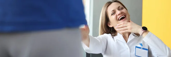 Doctora riéndose de paciente masculino en pantalones cortos en la clínica —  Fotos de Stock