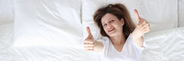 Vrouw liggend in bed en tonen duimen naar boven uitzicht — Stockfoto