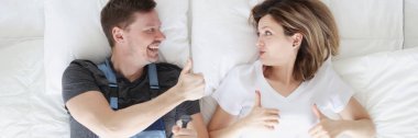 Woman lying in bed with plumber lover and showing thumb up top view
