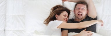 Woman sleeping on man in bed top view
