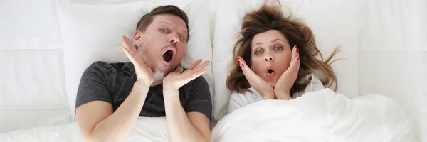 Surprised young woman and man lying in bed top view — Fotografia de Stock