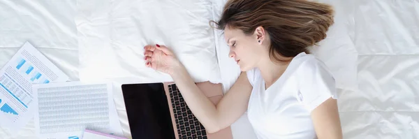 Жінка спить в ліжку з ноутбуком і документами вид зверху — стокове фото