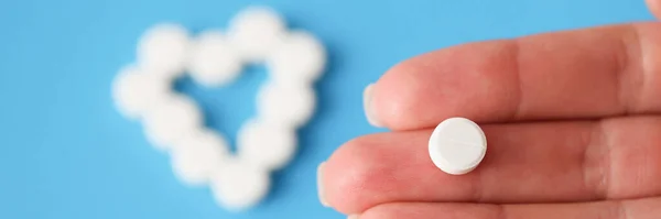 White pill lying on hand on background of heart closeup — Fotografia de Stock