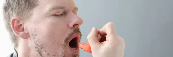 Young man holding his neck and inhaling medicine from inhaler — Φωτογραφία Αρχείου