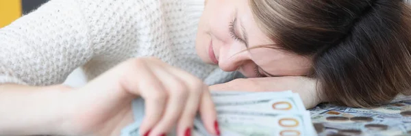 Young woman lying on pile of money and holding dollars in her hands — Foto Stock