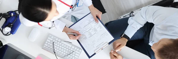 Lekarz zapisuje pacjentom dane medyczne w karcie. — Zdjęcie stockowe