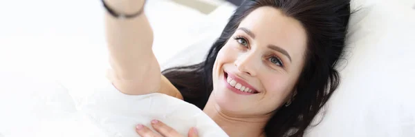 Jonge vrouw liggend in bed en het nemen van selfie — Stockfoto