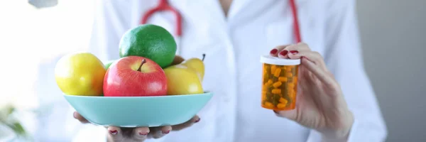 Doctor holding plate of fruit and jar of medicine closeup — Stock Photo, Image