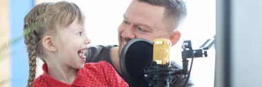 Man and girl are recording song on microphone