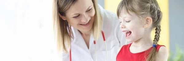 Smiling little girl with doctor pediatrician looks at transparent capsules Stock Picture