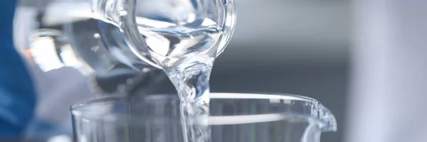 纯净水从玻璃瓶倒入玻璃杯中 — 图库照片