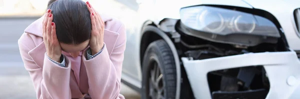 Eine aufgebrachte Frau sitzt kopfüber neben ihrem Auto — Stockfoto