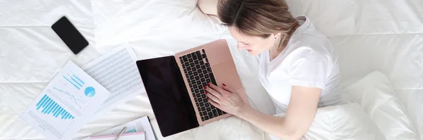 Mulher deitada na cama com laptop e documentos vista superior — Fotografia de Stock