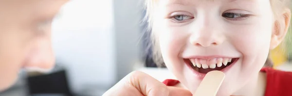 Оториноларинголог осматривает горло маленького ребенка лопаткой — стоковое фото