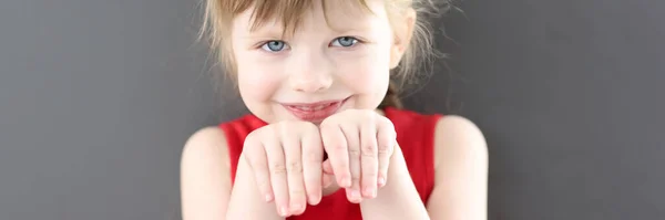 Портрет маленької красивої усміхненої дівчини з руками перед її обличчям — стокове фото