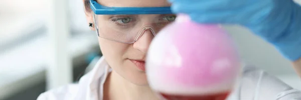 眼鏡の女性研究者がフラスコで化学実験を行っています — ストック写真