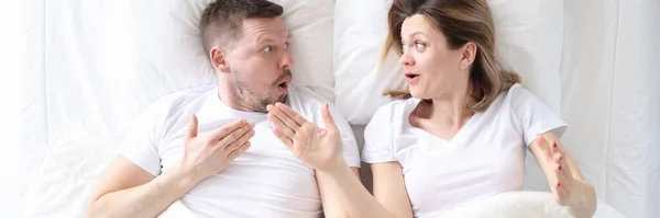 Sorprendido hombre y mujer discutiendo en cama vista superior —  Fotos de Stock