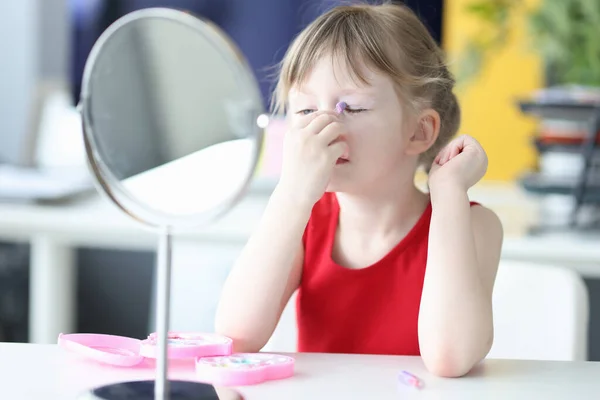 Adorable little girl doing makeup in front of mirror — Stock Photo, Image