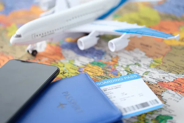 Smartfon i paszport z biletem leżą na mapie świata z małym samolotem — Zdjęcie stockowe