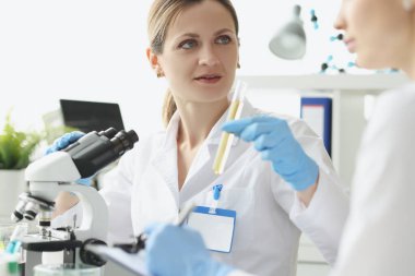 İki araştırmacı test tüpündeki sıvılar üzerinde kimyasal testler yapıyor.
