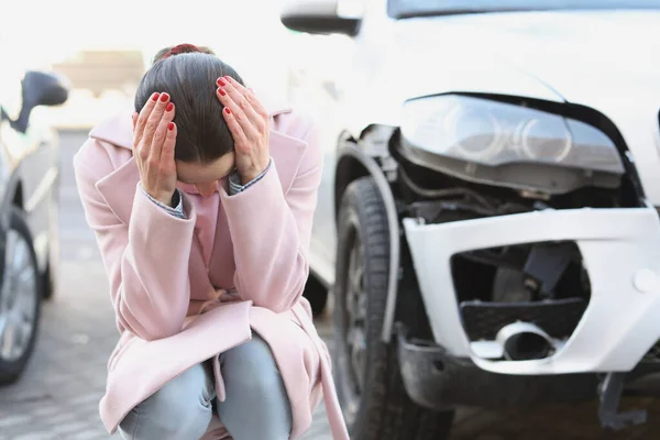Empörte junge Frau sitzt mit gesenktem Kopf neben Autowrack — Stockfoto