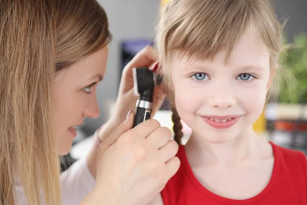 Vrouw kinderarts kijken trommelvlies van klein meisje met behulp van otoscoop in kliniek — Stockfoto