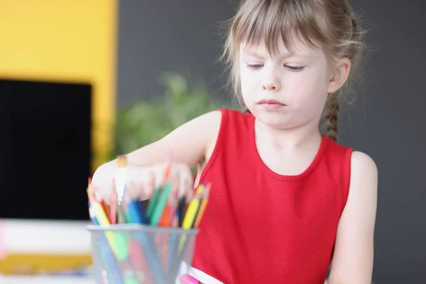 Little girl taking multicolored pencil from container — Stock Photo, Image