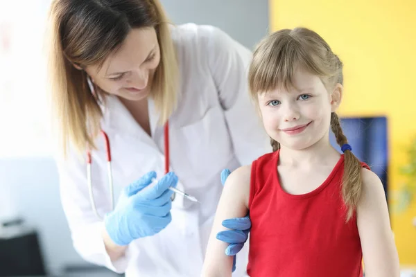 Doktorn injicerar en liten flicka i axeltätning — Stockfoto