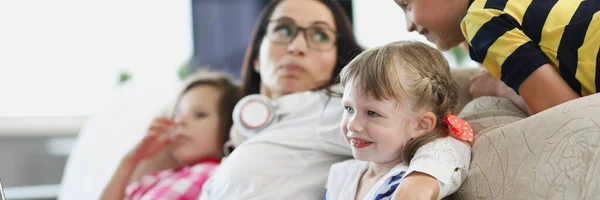 Junge Frau mit Kindern schaut Fernsehen im Wohnzimmer — Stockfoto