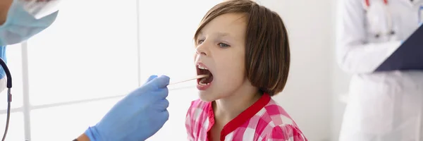 Médico mujer examina la garganta de una niña —  Fotos de Stock