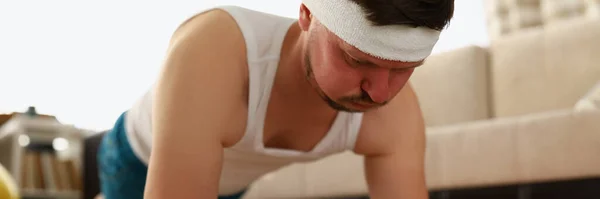 Мужчина выполняет упражнения на доске в квартире на ковре — стоковое фото