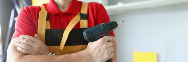 Um homem de roupa de trabalho tem uma pistola de parafuso — Fotografia de Stock