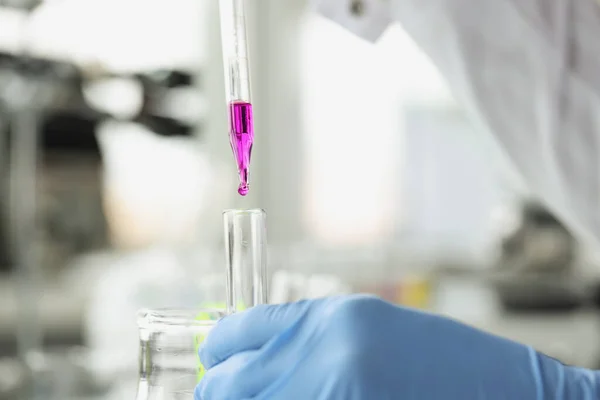 Científico deja caer líquido púrpura de la pipeta en el tubo de ensayo —  Fotos de Stock