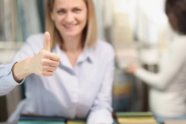 Женщина-покупатель улыбается показывая большие пальцы вверх жестом в магазине — стоковое фото