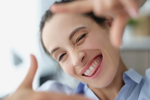 Glad leende kvinna gör fotoram med händerna — Stockfoto