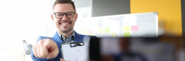 Genç adam cep telefonu ekranını parmağıyla gösteriyor
