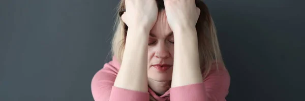 Mujer triste con los ojos cerrados sosteniendo la cabeza con las manos — Foto de Stock