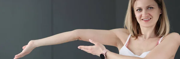 Fiatal mosolygós nő mutatja hajlított karját — Stock Fotó