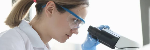 Woman scientist with glasses conducts research through microscope — Foto Stock