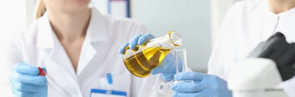 Two researchers in laboratory examine golden liquid in test tube — Stock fotografie